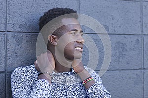 Handsome young black man stands in front of gray block wall