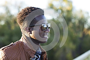 Handsome young black man in sunglasses and a leather jacket on a