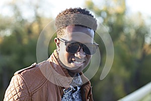 Handsome young black man in sunglasses and a leather jacket on a