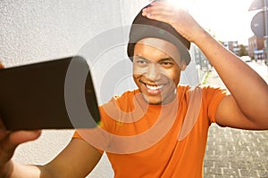 Handsome young black man taking selfie with mobile phone on street