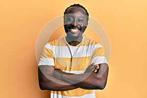 Handsome young black man wearing casual yellow tshirt happy face smiling with crossed arms looking at the camera