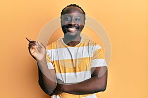 Handsome young black man wearing casual yellow tshirt smiling happy pointing with hand and finger to the side