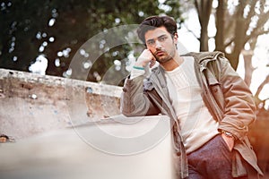Handsome young bored man leaning on a wall. Outdoor