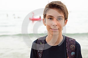 Handsome young boy at beach in Alicante. Beautiful calm smiling teen boy at Mediterranean sea coast in Spain. Travel, summer