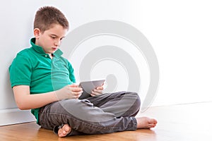 Handsome Young Boy with Tablet Leaning on Wall