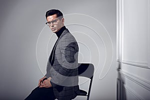 Profile portrait of a handsome, elegantly man in black-gray suit and eyeglasses,  on white background.