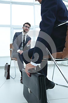 Handsome young business man holding a black briefcase in his han