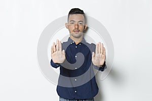 Handsome young business man with open hand doing stop sign with serious expression defense gesture isolated on white background
