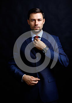 Handsome young business man standing on black