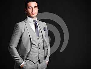 Handsome young business man standing on black photo