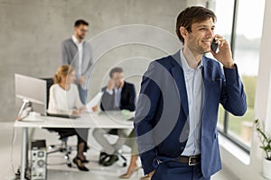 Handsome young business man standing confident in the office and suing mobile phone