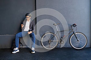 Handsome young business man in suit with a bicycle using smartphone on city street.