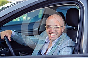 Handsome young business smiling man looking out of his new car window