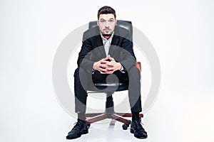 Handsome young businessman with beard sitting in black office chair