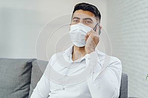 Handsome young businessman with face mask talking on the phone