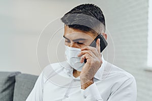 Handsome young businessman with face mask talking on the phone