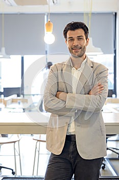 Handsome young businessman with folded arms in the office. Cheerful self confident man with crossed hands portrait. Business,