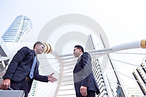 Handsome young businessman is introducing his self to elder businessman or customer by giving his hand to him at appointment