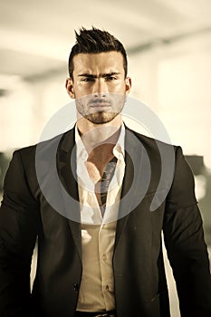 Handsome young businessman in office building, standing