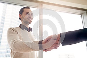 Handsome young businessman shaking female hand, deal or business