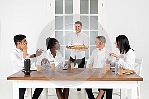 Handsome young businessman in shirt holding box with pizza in office