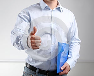 Handsome young businessman showing ok standing with folder