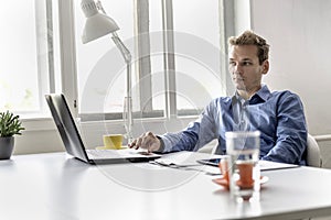 Handsome young businessman sitting at his office desk working