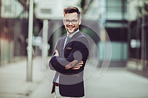 Young businessman smartly dressed while standing outdoors at the city street photo