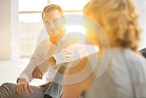 Handsome young businessman smiling while sitting on the floor with collegues in new office