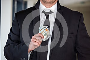 handsome young businessman in a stylish jacket from a suit with a large sum of dollars.