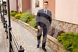 Handsome young businessman walking on city street in the morning going to work in office. Urban lifestyle of young profes