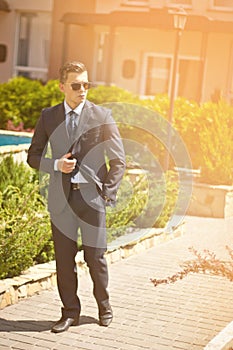 Handsome young businessman walking on city street in the morning going to work in office. Urban lifestyle of young profes