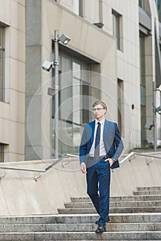 handsome young businessman walking down stairs in business district