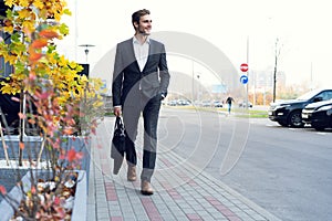 A handsome young businessman walking on the street in the sunset