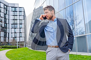 Handsome young businessman on a work call outside the office in a business park