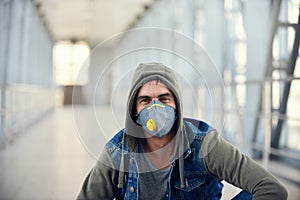 Handsome young caucasian man in hoody on the street with a medical face mask on. Coronavirus concept photo