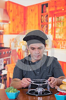 Handsome young cheff preparing a gourmet Swiss fondue dinner on wooden table in kitchen background