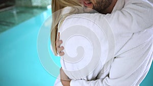 Handsome young couple embracing by the indoor swimming pool