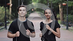 Handsome Young Couple in Headphones Looking Relaxed Smiling Running in Park Concept Healthy Lifestyle.