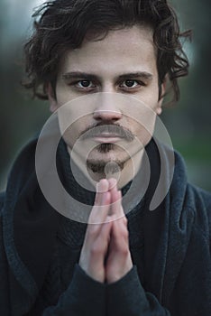 Handsome young curly man sincerely praying. religion concept