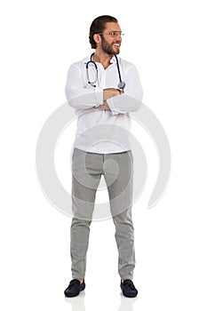Handsome Young Doctor Is Standing With Arms Crossed And Looking At The Side. Front View
