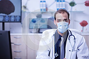 Handsome young doctor with a stethoscope hanging on his neck and wearing a mask over his face