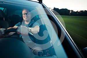 Handsome young driver driving hic car fast yet safely on the road