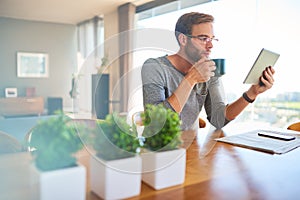 Handsome young european architect drinking coffee and reading at home