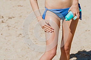 Handsome young female,applying sun tan cream,at the beach.