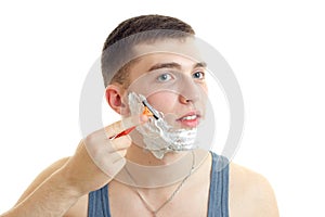 Handsome young guy shaves his beard machine using shaving foam on your face closeup