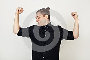 Handsome young guy, student with self-confident facial expression showing arm muscles, smiling proudly. Fitness concept