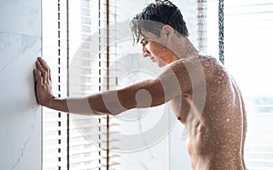 Handsome young guy taking hot shower in bathroom