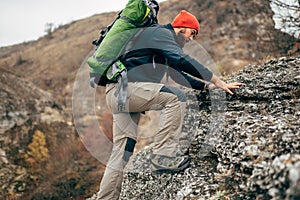 Handsome young hiker man hikking in the mountains. Traveler bearded man trekking during his journey.
