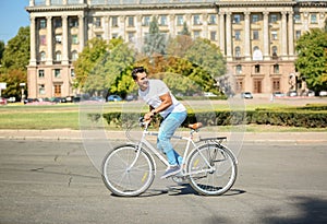 Handsome young hipster man riding bicycle